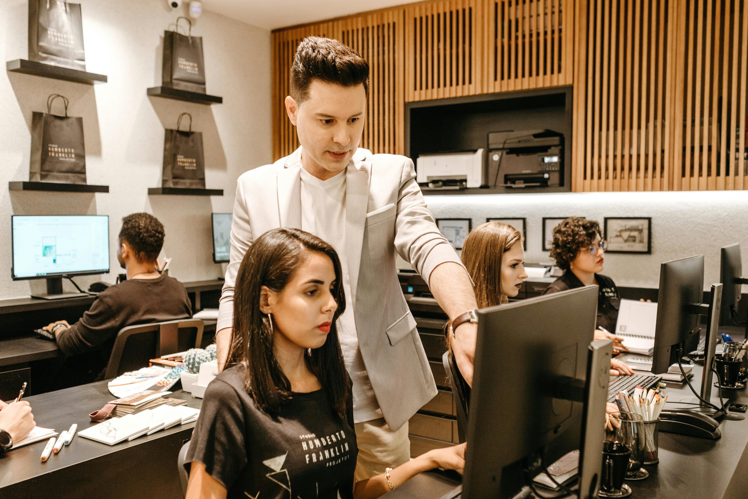 A man assisting a woman at her computer.